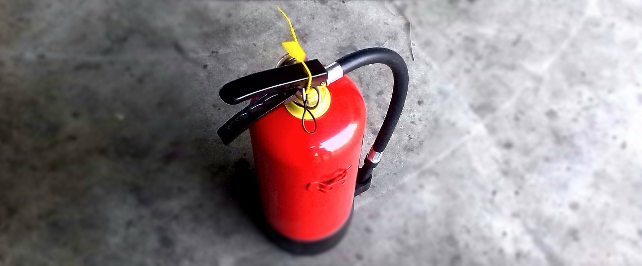 A fire extinguisher is sitting on the ground.